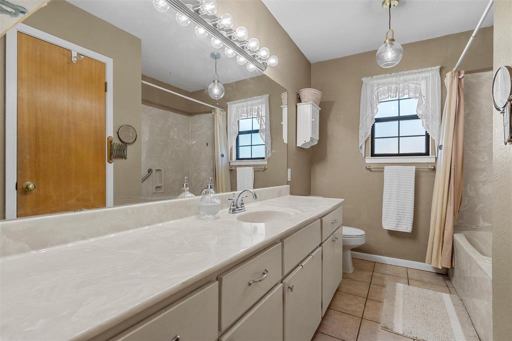 117 North 9th Street Lott, TX 76656 - Photo 15 of 28 Bathroom featuring plenty of natural light, vanity, light tile patterned floors, and shower / bathtub combination with curtain
