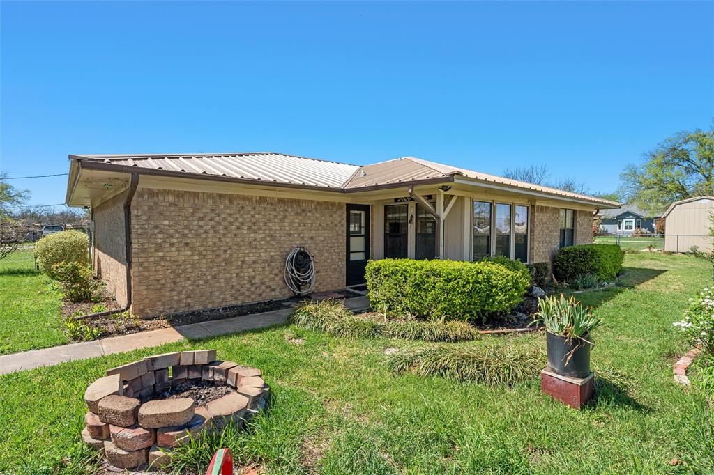 117 North 9th Street Lott, TX 76656 - Photo 22 of 28 Back of house featuring brick siding, a fire pit, and a metal roof