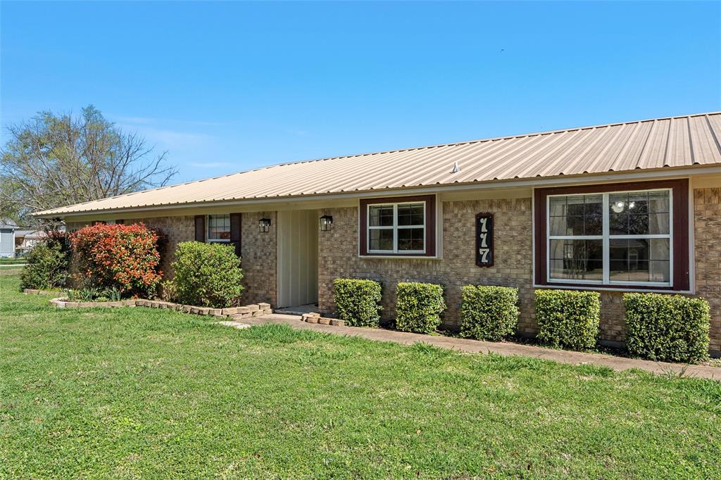 117 North 9th Street Lott, TX 76656 - Photo 24 of 28 Ranch-style home featuring a front lawn, brick siding, and a metal roof