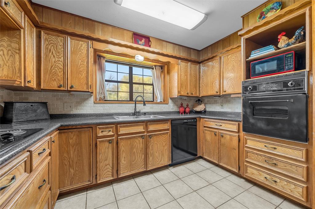 117 North 9th Street Lott, TX 76656 - Photo 5 of 28 Kitchen featuring wood finish cabinets, black appliances, decorative backsplash, open shelves, and light tile patterned flooring