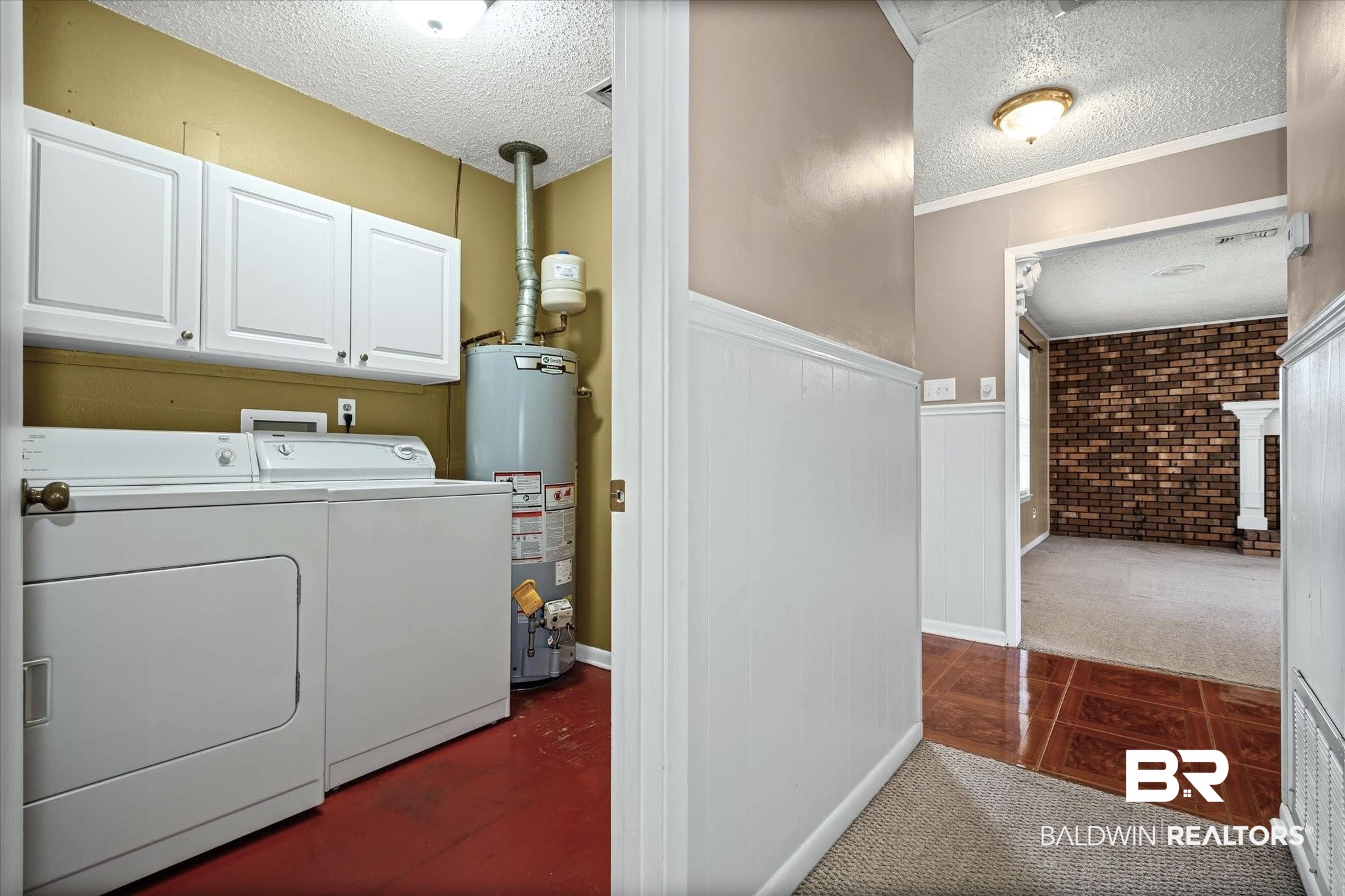 8090 Murray Hill Road Irvington, AL 36544 - Photo 28 of 40 Laundry area with a textured ceiling, a wainscoted wall, gas water heater, cabinet space, and dark colored carpet
