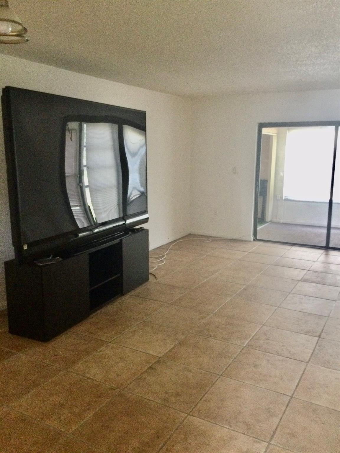 9233 Southwest 8th Street, Unit 110 Boca Raton, FL 33428 - Photo 4 of 14 a living room with a black furniture and a flat screen tv