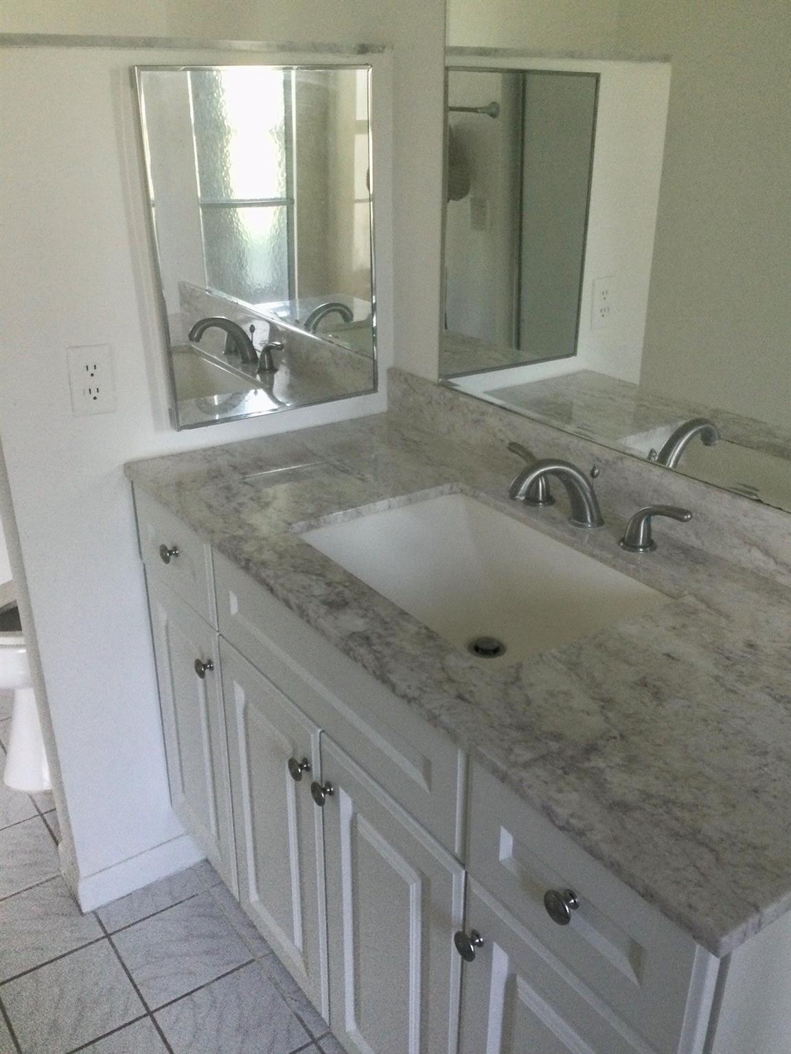9233 Southwest 8th Street, Unit 110 Boca Raton, FL 33428 - Photo 8 of 14 a bathroom with a granite countertop sink and a mirror