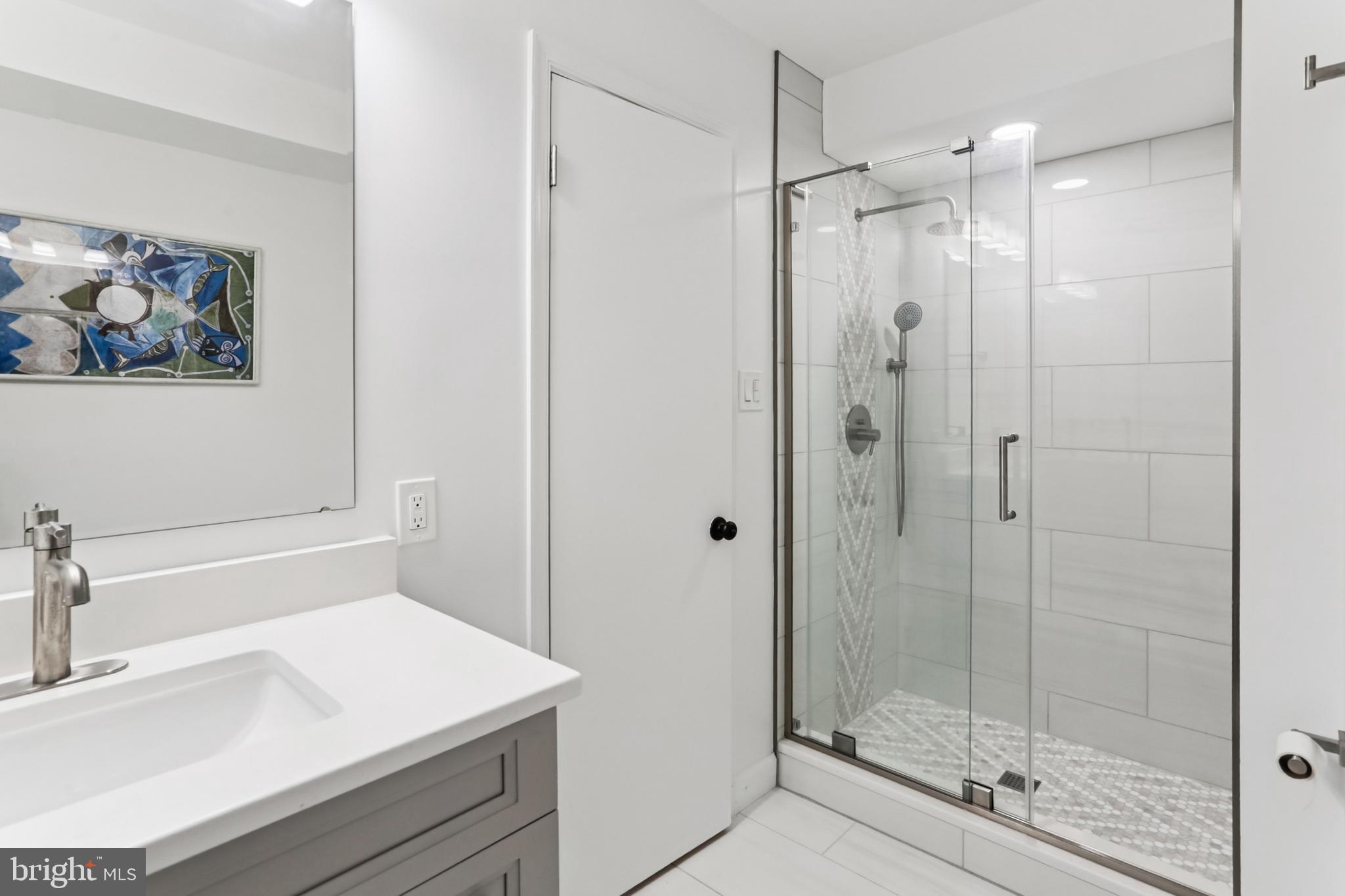 10233 Gainsborough Road Potomac, MD 20854 - Photo 20 of 50 a bathroom with a shower sink vanity and mirror