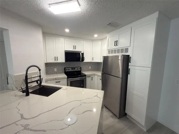 a kitchen with stainless steel appliances a refrigerator stove microwave and sink