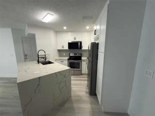 a kitchen with kitchen island a sink stove and refrigerator