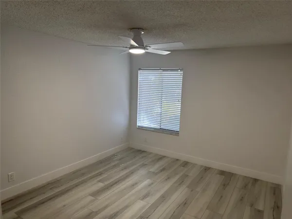 an empty room with a fan & a window