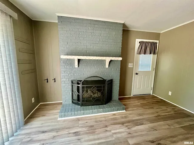 a view of a livingroom with wooden floor and a fireplace
