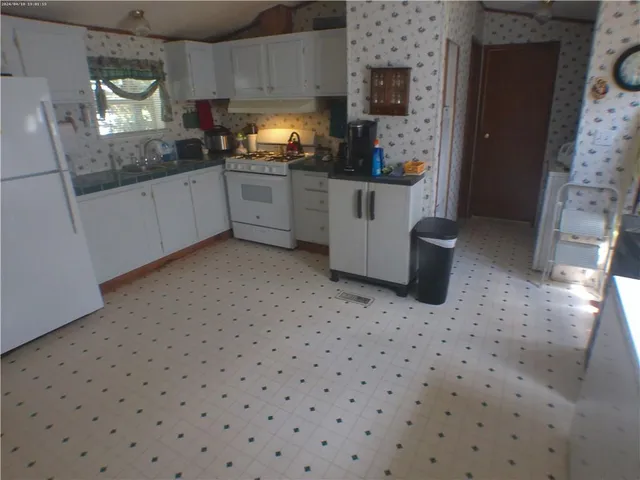 a kitchen with granite countertop white cabinets white appliances and a sink