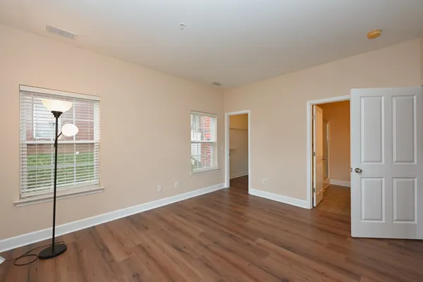 a view of an empty room with wooden floor and closet