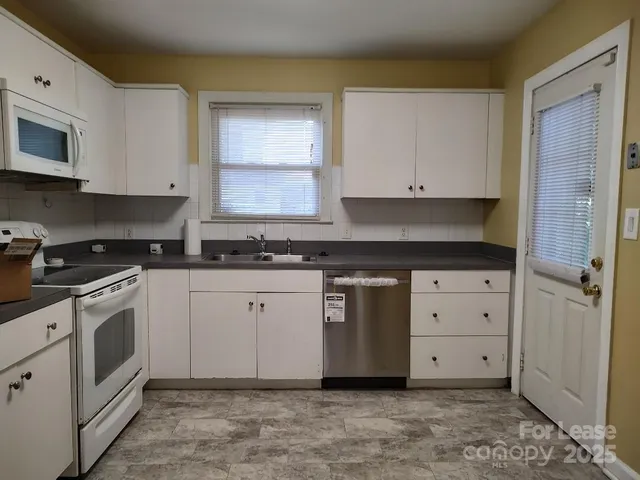 a kitchen with granite countertop white cabinets and stainless steel appliances