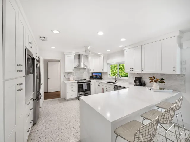 a large kitchen with stainless steel appliances kitchen island granite countertop a large stove a refrigerator a oven and a sink with large countertops