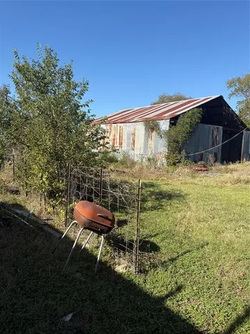 a backyard of a house with table and chairs under an umbrella