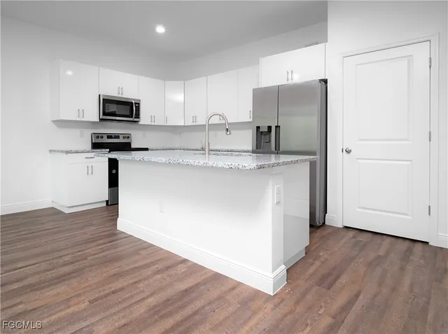 a kitchen with stainless steel appliances granite countertop a refrigerator a stove top oven a sink and dishwasher with wooden floor