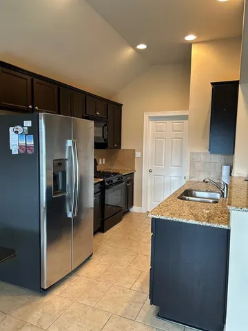 a kitchen with stainless steel appliances granite countertop a refrigerator a sink and a stove