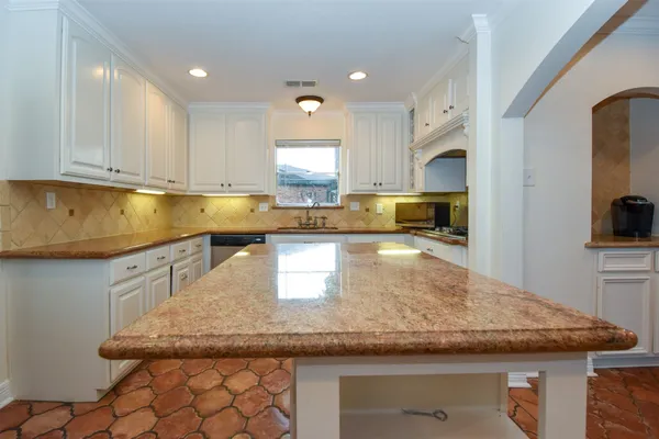 a kitchen with kitchen island granite countertop a sink a counter top space and cabinets