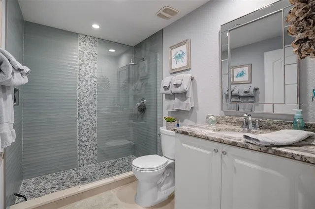 a bathroom with a granite countertop sink a toilet a mirror and shower