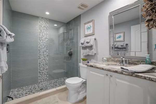 a bathroom with a granite countertop sink a toilet a mirror and shower
