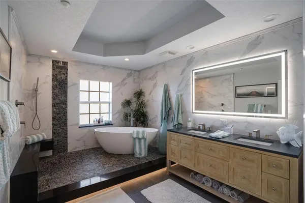 a bathroom with a granite countertop tub sink mirror and window