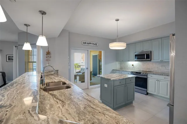 a kitchen with stainless steel appliances granite countertop cabinets a stove a sink a center island and a window