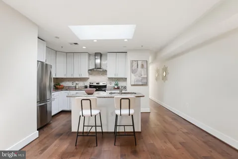 a kitchen with wooden floors and white stainless steel appliances