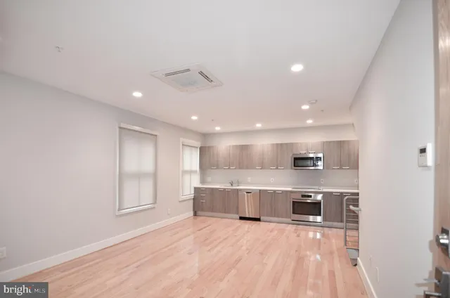 a kitchen with stainless steel appliances kitchen island granite countertop a table chairs sink and microwave