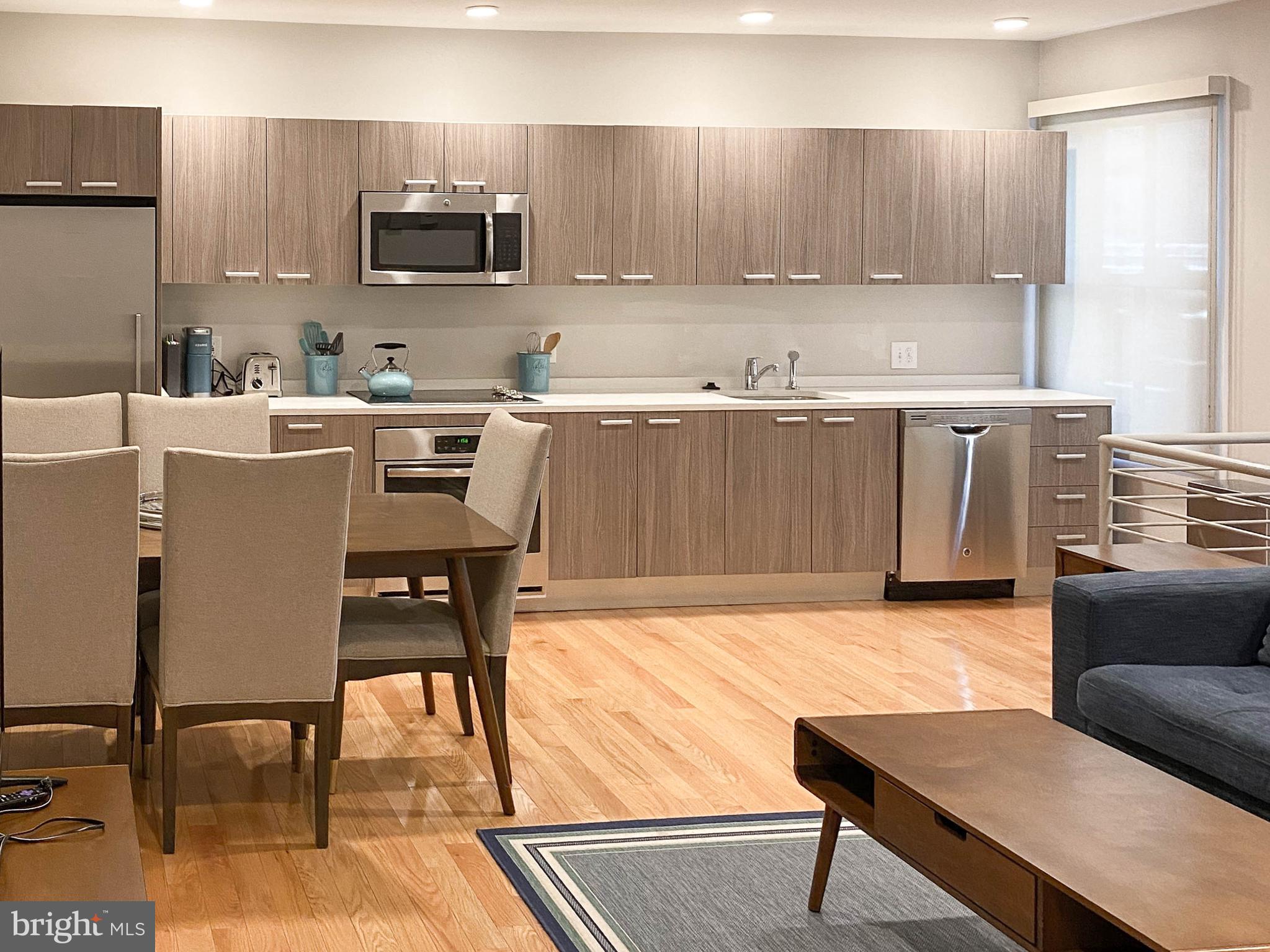 1072 Thomas Jefferson Street Northwest Washington, DC 20007 - Photo 32 of 58 a kitchen with stainless steel appliances kitchen island granite countertop a table chairs sink and microwave