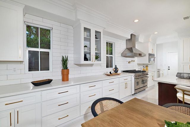 a kitchen with white cabinets a stove a sink and a potted plant