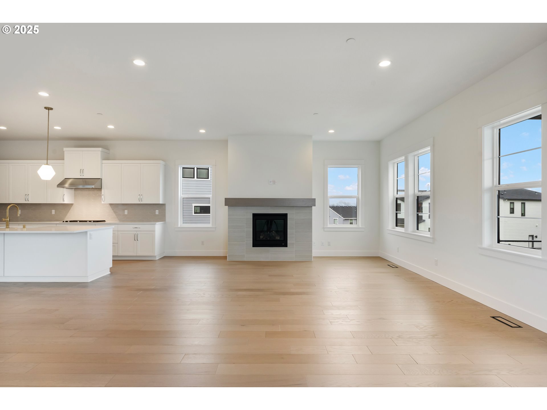 386 West Fir Loop Washougal, WA 98671 - Photo 15 of 45 a view of an empty room with wooden floor and a kitchen