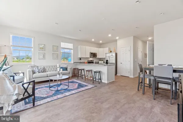 a living room with furniture a rug kitchen view and a window