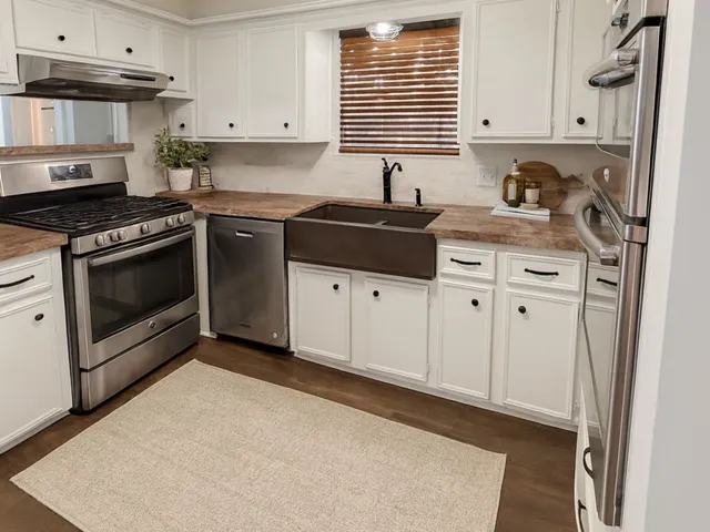 a kitchen with granite countertop a sink a stove and cabinets