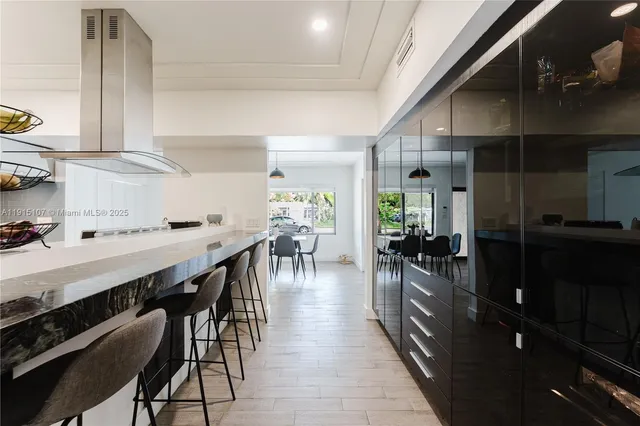 a dining hall with stainless steel appliances a stove top oven a dining table and chairs with wooden floor