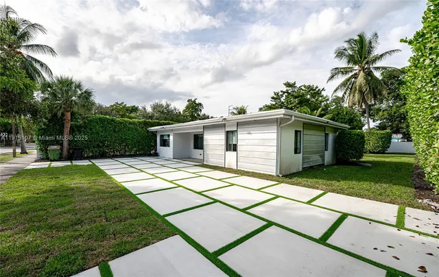 a backyard of a house with table and chairs plants and large tree