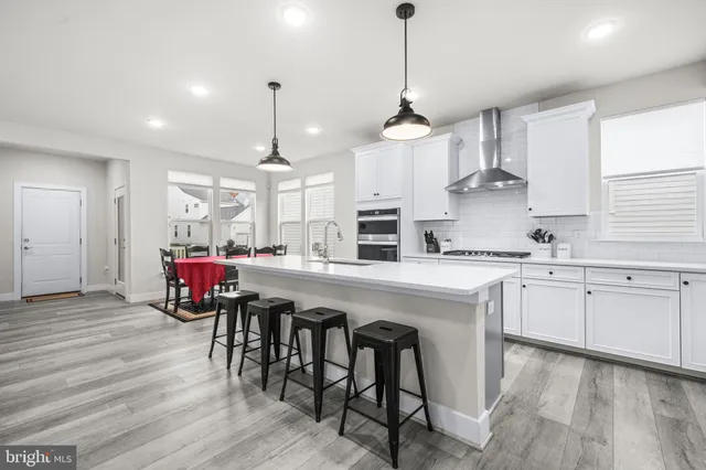 a kitchen with stainless steel appliances granite countertop a kitchen island hardwood floor sink stove dining table and chairs