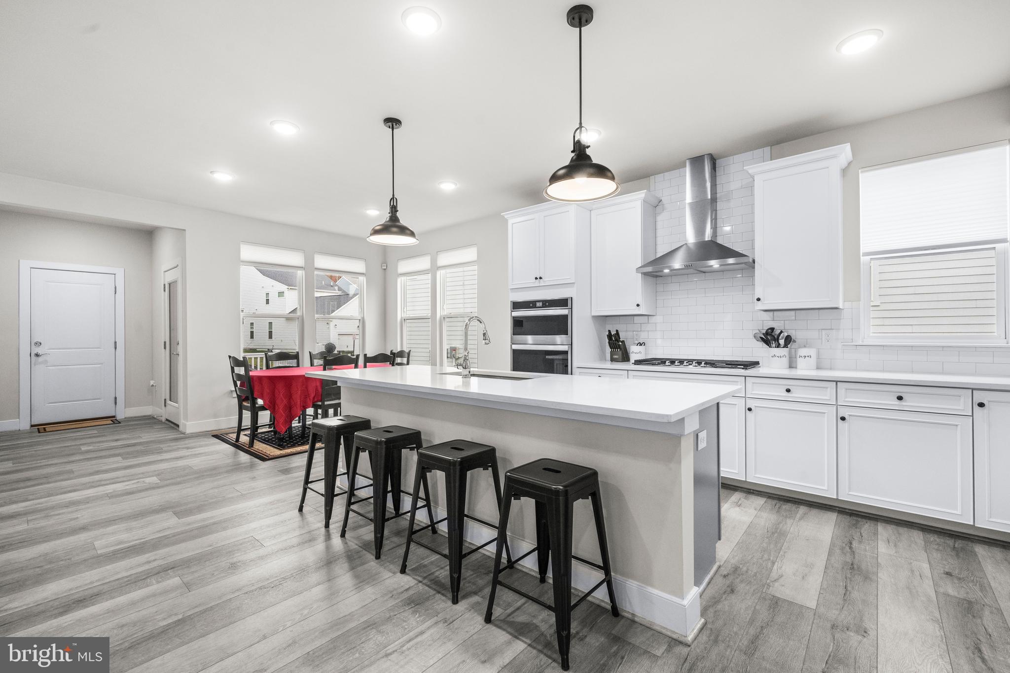1814 River Heritage Boulevard Dumfries, VA 22026 - Photo 3 of 55 a kitchen with stainless steel appliances granite countertop a kitchen island hardwood floor sink stove dining table and chairs