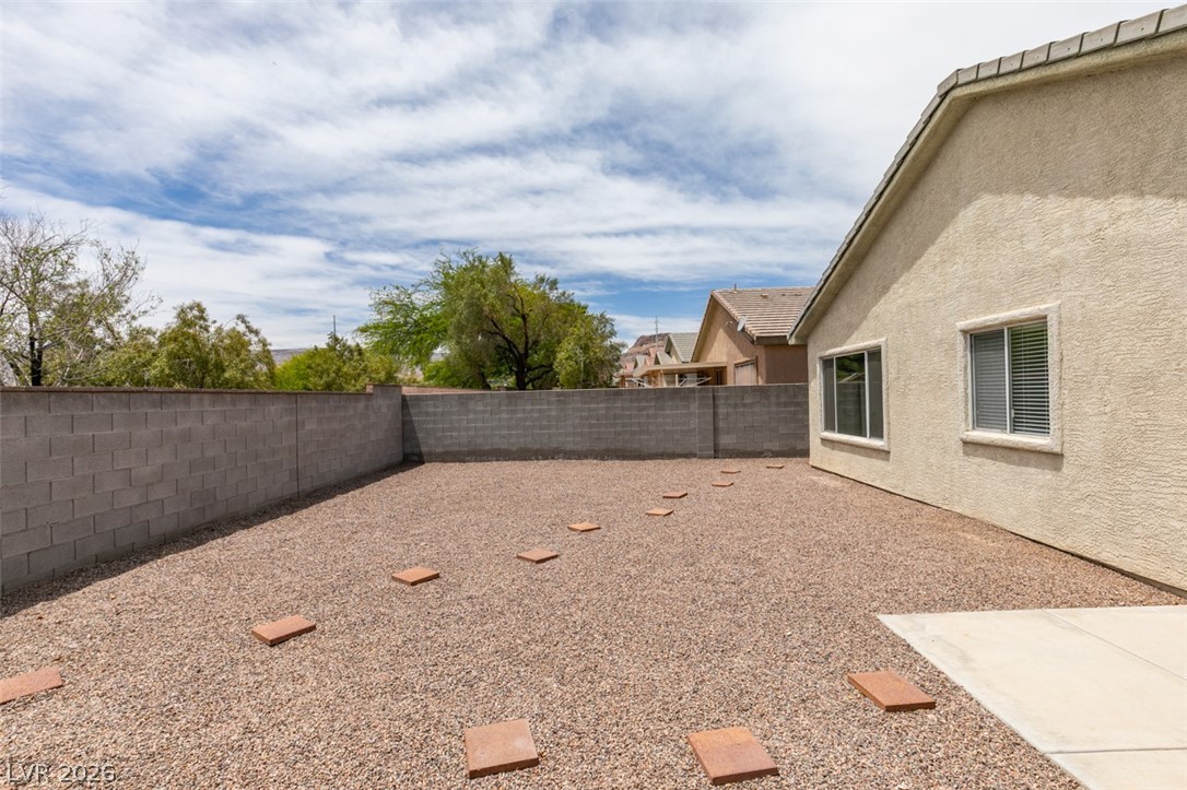 10959 Pumpkin Ridge Avenue Las Vegas, NV 89135 - Photo 31 of 51 A private desert yard featuring a concrete block fence and stepping stones, ideal for low-maintenance outdoor living.
