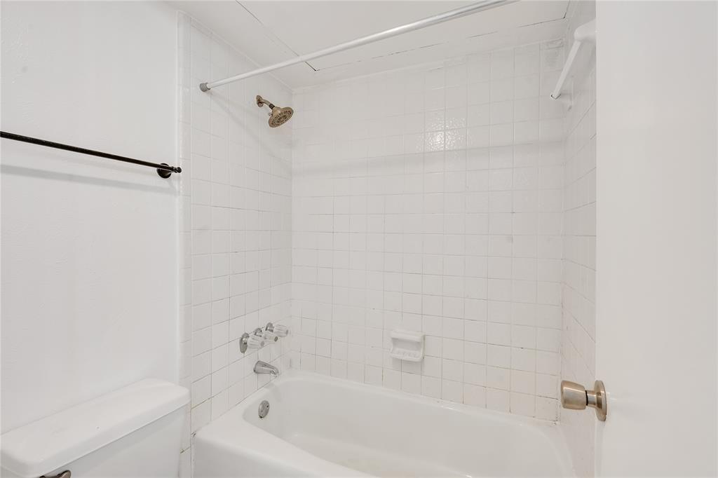 4525 North O'Connor Road, Unit 1184 Irving, TX 75062 - Photo 12 of 20 Bathroom featuring a bathtub with white tile surround, a shower head, and a toilet
