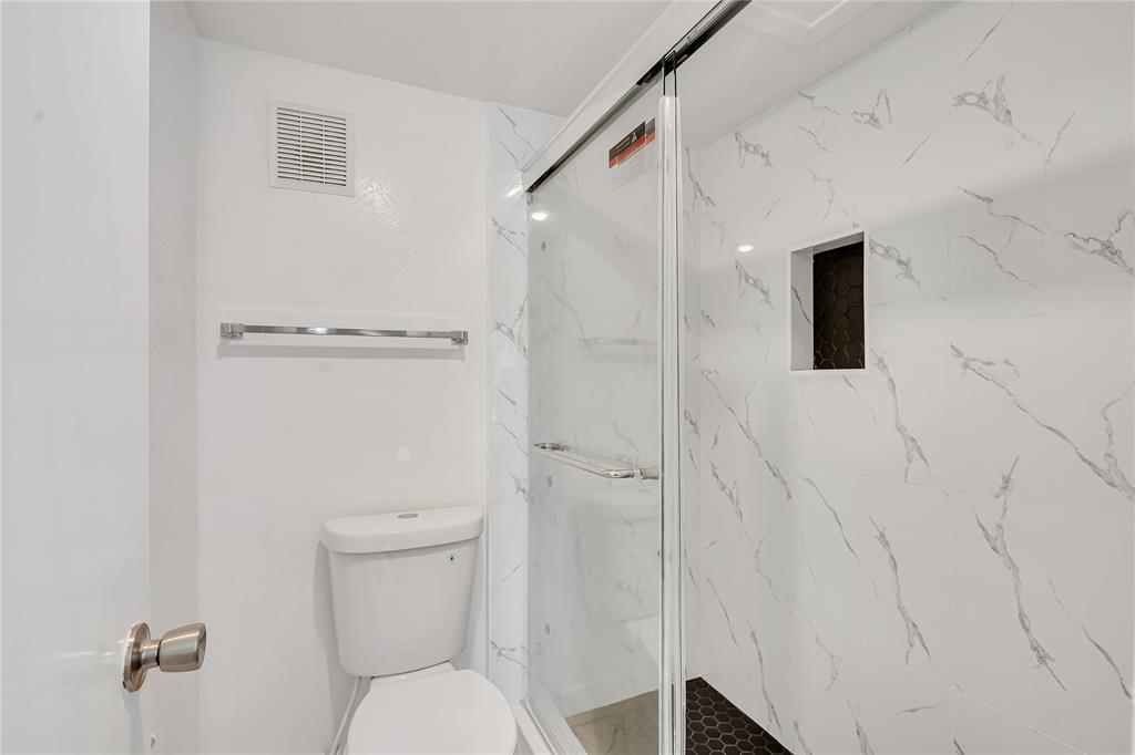 4525 North O'Connor Road, Unit 1184 Irving, TX 75062 - Photo 16 of 20 Bathroom featuring a shower with white marble-style tiled walls and a dark hexagonal tiled floor, a built-in shower niche, and a white toilet