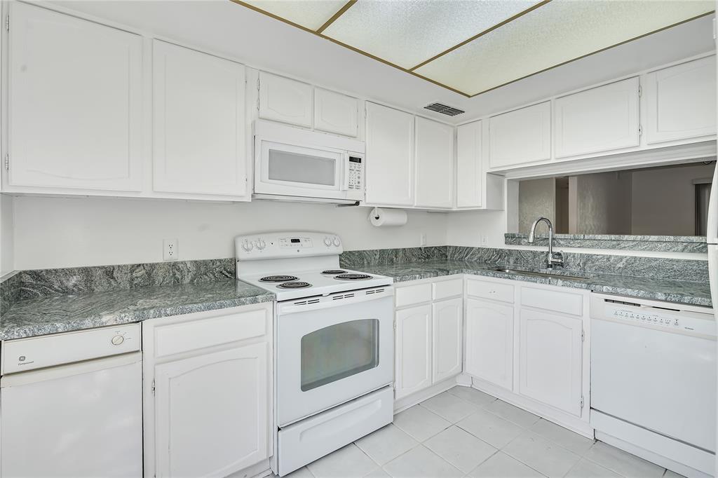 4525 North O'Connor Road, Unit 1184 Irving, TX 75062 - Photo 4 of 20 The kitchen features white cabinetry, granite countertops, a white electric range, a microwave, and a dishwasher