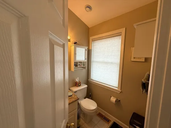 a bathroom with a granite countertop toilet and a sink