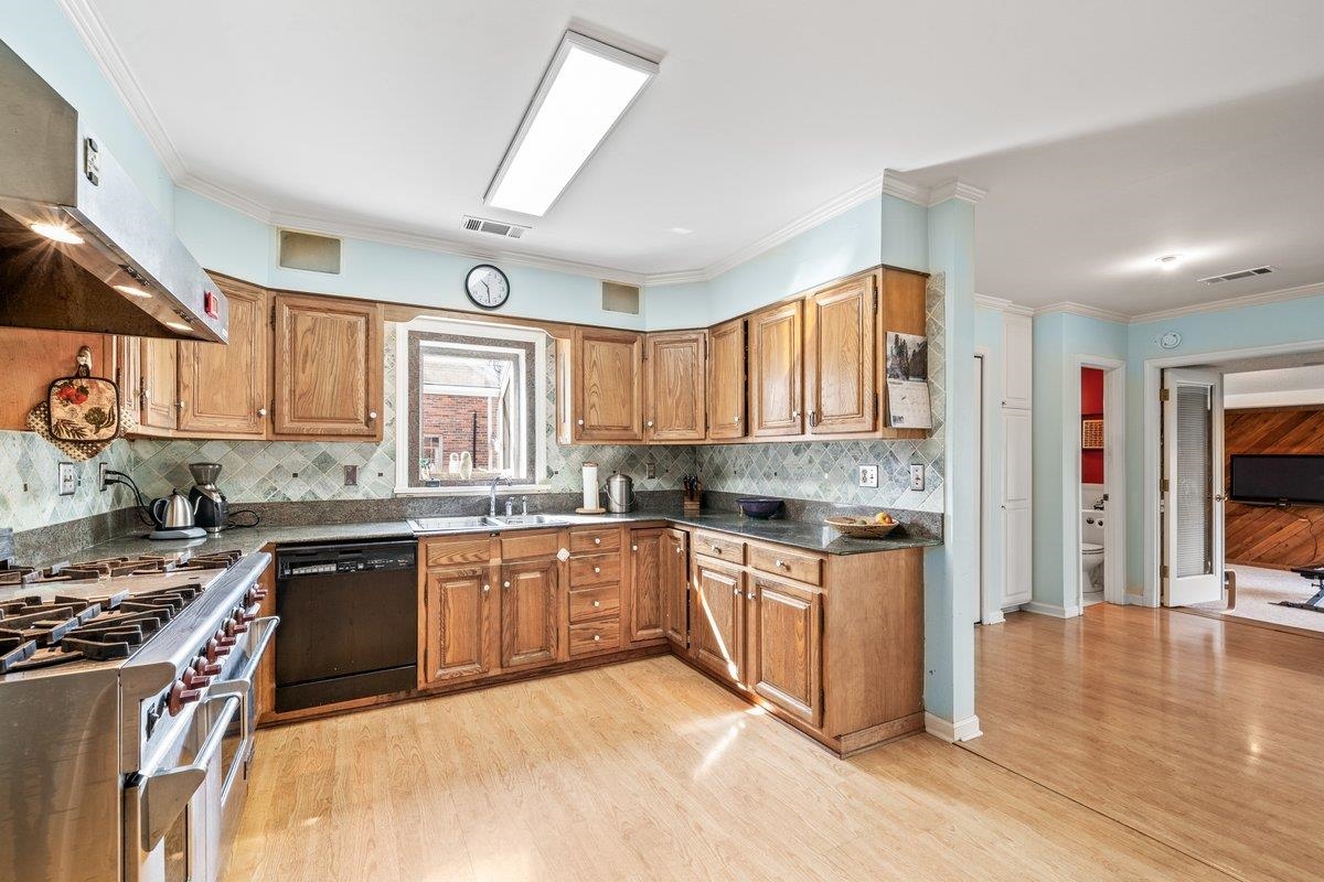 353 Colonial Road Memphis, TN 38117 - Photo 15 of 37 Kitchen with double oven range, ornamental molding, wood finish cabinets, black dishwasher, and light wood-type flooring