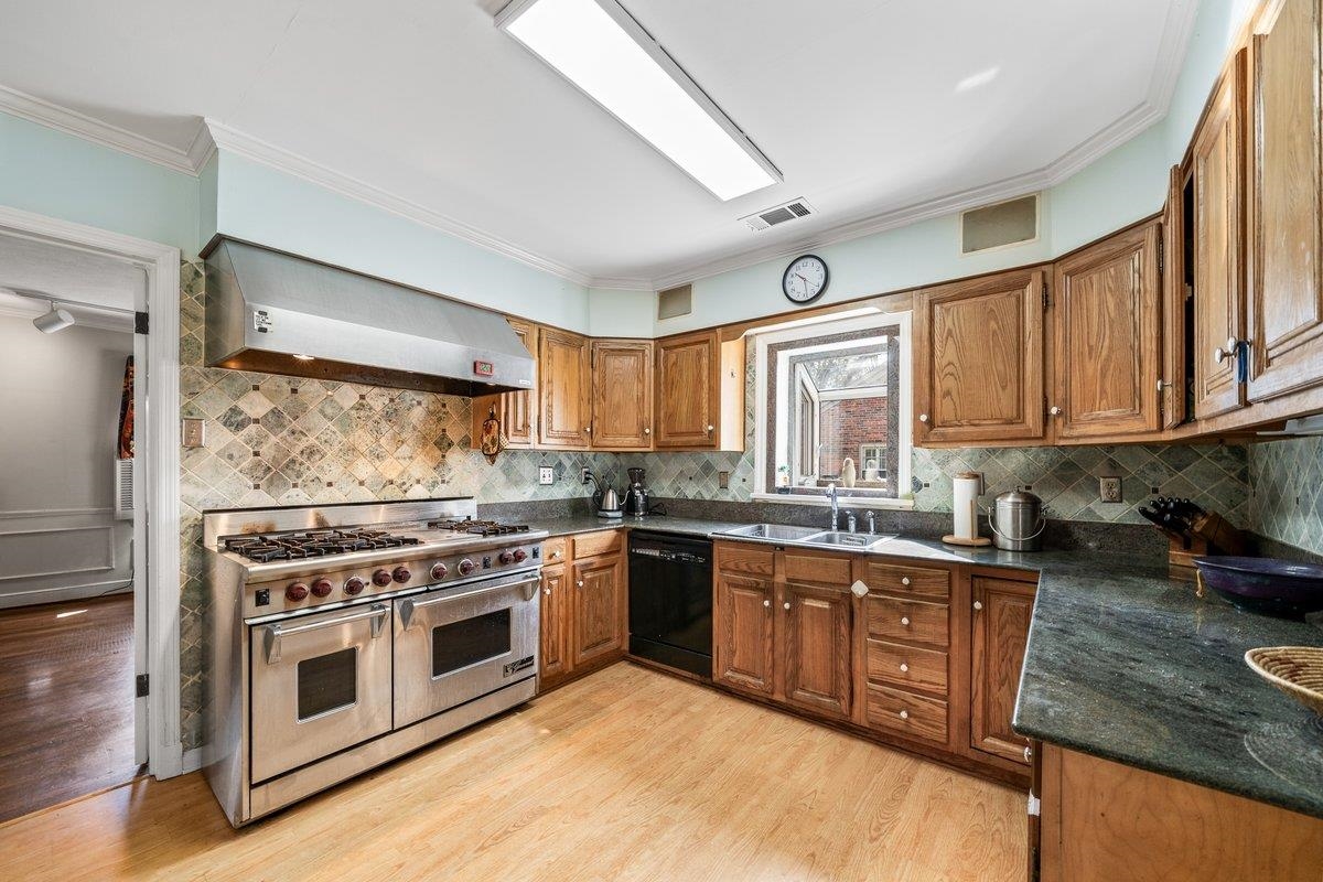 353 Colonial Road Memphis, TN 38117 - Photo 16 of 37 Kitchen with double oven range, wood finish cabinetry, ornamental molding, black dishwasher, and light wood finished floors