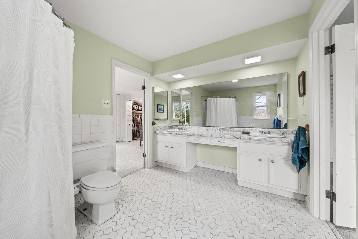 353 Colonial Road Memphis, TN 38117 - Photo 25 of 37 Bathroom with double vanity, tile walls, curtained shower, a wainscoted wall, and a spacious closet