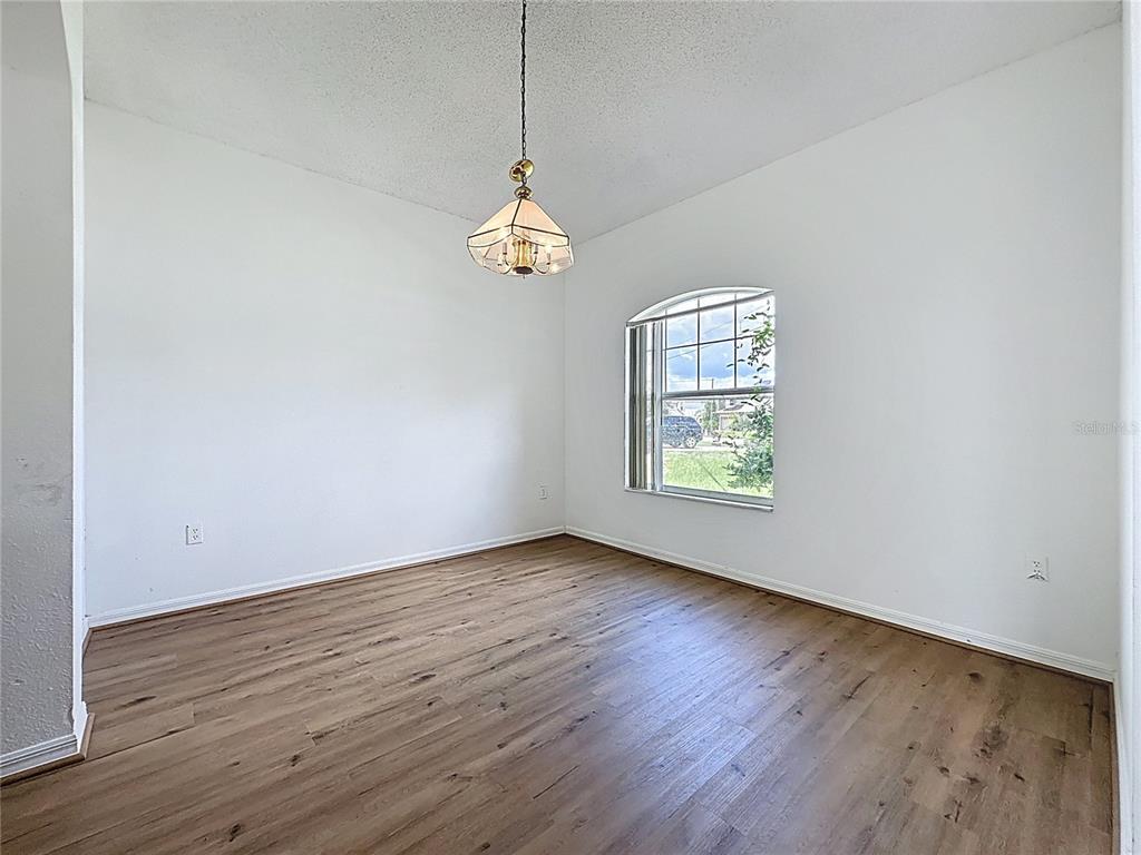 1430 Nelson Brook Way Kissimmee, FL 34759 - Photo 13 of 37 an empty room with wooden floor chandelier and window