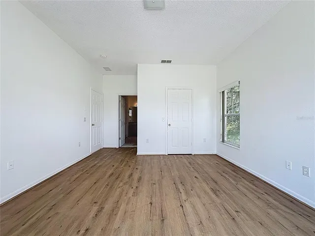 an empty room with wooden floor and windows