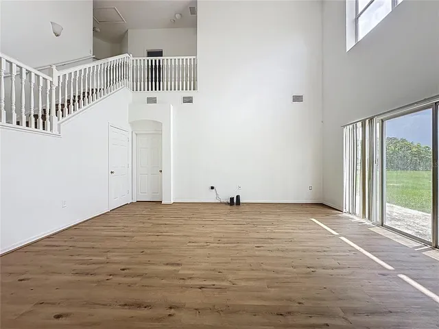 a view of an empty room with wooden floor and windows