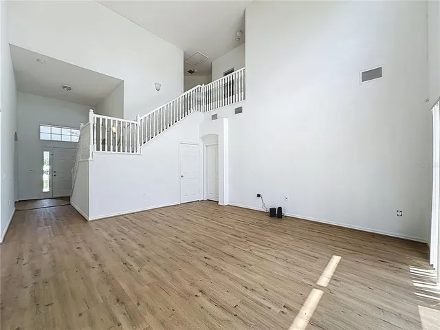 a view of an empty room with wooden floor and stairs