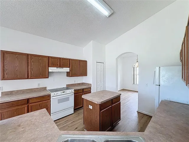 a living room with stainless steel appliances kitchen island granite countertop a stove a sink and a refrigerator