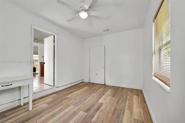 a view of empty room with wooden floor and fan