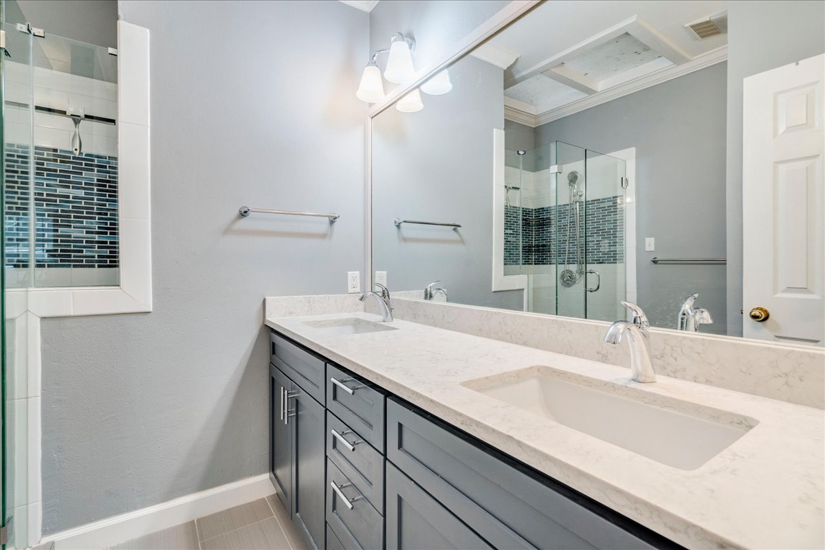 3809 Spicewood Springs Road, Unit 127 Austin, TX 78759 - Photo 14 of 29 Double vanity with stone counters and a glass-enclosed shower create a practical bathroom.